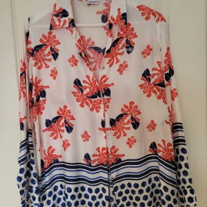 Silkig blus - Silkig blus med blommönster. Väldigt fin till kontoret om man vill piffa upp stilen lite. Använts ett tiotal gånger. 