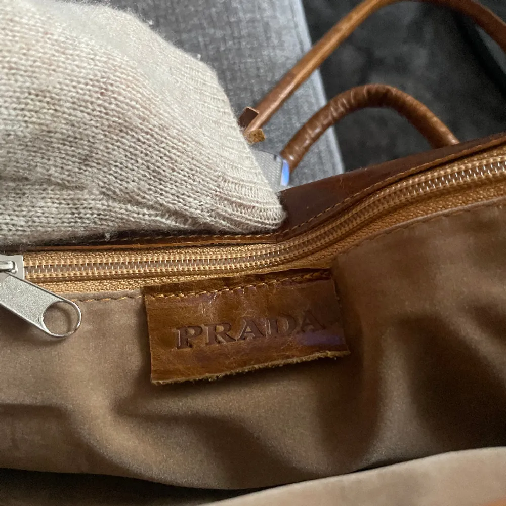 Superfin vintage Prada väska i läder, inslagen i sammet på insidan. En nyckel medföljer (se bild 1) då man kan låsa väskan. Såklart äkta och är i jättebra skick med tanke på dens ålder, lite skrynklig bara men det har sin charm. Många fack o rymmer mycket. Väskor.