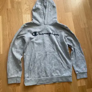 En Champion hoodie med luva, stl 150/155. Två mindre hål på vardera ärm. Skicket på tröjan 6/10.