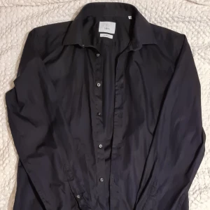 Bläck skjorta stl m svart köpt på MQ. - Skjorta Bläck använd 1 gång i storlek medium och nyskick säljes p.ga för liten för mig. Fläckfritt, rökfritt o djurfritt hem.