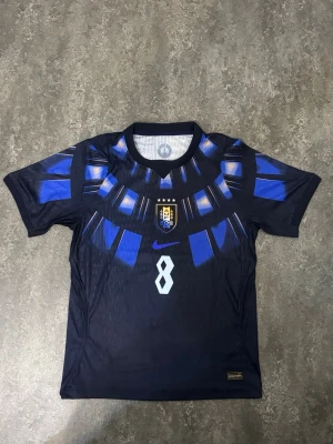 Uruguay Away Tröja vm-26 - Snygg Uruguay fotbollströja med F. Valverde #8  Tröjan är endast använd en gång och är i mycket fint skick, som ny. Inga skador eller fläckar.  Pris: 400kr – tycker det är ett bra och rimligt pris för tröjan. Priset kan diskuteras vid snabb affär.  Skickas snabbt och packas ordentligt.