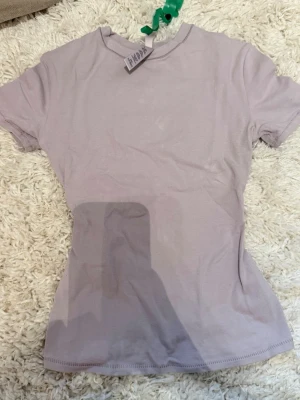 Skims Ljuslila kortärmad t-shirt XXS - En enkel och stilren ljuslila t-shirt i kortärmad modell. Tillverkad i mjuk bomull med lite elastan för extra stretch och bekväm passform. Perfekt basplagg till alla outfits.