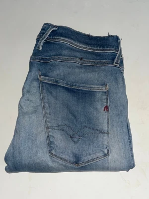 Replay Anbass jeans  - Ljusblåa Replay Anbass jeans som har ett mjukt matrial. Midja 38cm, längd 105cm. Obs bak på jeansen är tyget något förtunnat - se närbild. Jag har tyvärr ingen bild på när jag bär jeansen på. För bättre inblick i passformen rekommenderar jag att googla på modellnamnet. För storleksguide kolla måtten noggrant då jeansen alltid kan vara uppsydda heller krympta och jag ej tar emot returer :) (r19)