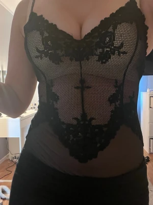 Svart spetsbody med tunna axelband från Intimissimi storlek S - Säljer en svart body med spets och tunna axelband och djup urringning. Bodyn har ett detaljerat spetsmönster framtill och transparent tyg på sidorna. Perfekt för dig som vill ha något snyggt och trendigt under kläderna. Storlek S från Intimissimi 