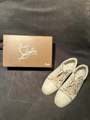 Christian Louboutin Sneakers - Unika skor från Christian Louboutin | Storlek 45 | Färg: Vit med guldiga detaljer. Skiftande färg mellan blå/rosa vid hälen | Box finns | Skriv vid frågor | Sömen har släppt lite vid insidan av foten |