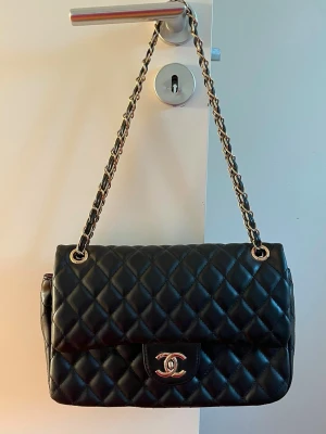 Svart   handväska - Säljer en klassisk svart quiltad handväska  med kedjerem och guldfärgade detaljer. Väskan  är tillverkad i läder. Perfekt för dig som vill ha en tidlös och elegant accessoar.