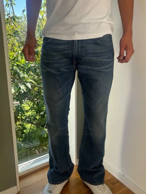 Bootcut Levis 527 Vintage Jeans - Levi's 527 vintage bootcut jeans. Snygga fades framtill som ger jeansen extra karaktär och en snygg bootcut passform. Färg: Blå med snygga fades framtill Passform: Bootcut Storlek: W34 L32 Skick: A-B Grade Mått (±1 cm): A: 43 cm B: 107 cm C: 23 cm D: 30 cm Passar bra på modellen på bilden som är 189 cm lång och väger 82 kg. Tveka inte att höra av dig vid frågor eller funderingar. Skickas snabbt!