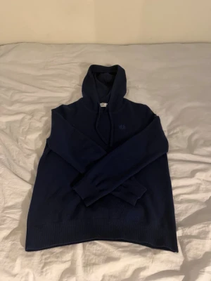 Mörkblå stickad hoodie - Mysig mörkblå stickad hoodie med huva och långa ärmar. Perfekt för kyliga dagar och enkel att matcha med jeans eller mjukisbyxor. Storlek xs och är slutsåld ofta kostar runt 1200 ny. Använd två gånger. Säljer eftersom den är för liten. 