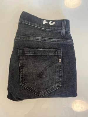 Dondup George  jeans  - W31 l31Snygga svarta fondue  jeans i slim fit-modell med klassisk femficksdesign och diskret detalj på bakfickan. Jeansen har normal midja och raka ben, perfekta för en avslappnad men stilren look. Tillverkade i mjukt denimtyg med lite stretch för extra komfort.