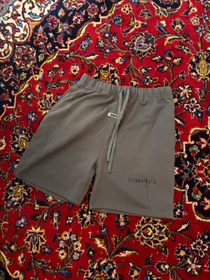 Bruna shorts med snörning ESSENTIALS - Snygga bruna shorts från ESSENTIALS med elastisk midja och snörning. Tillverkade i mjukt material och har diskret logga broderad på benet. Perfekta för en avslappnad och trendig look.