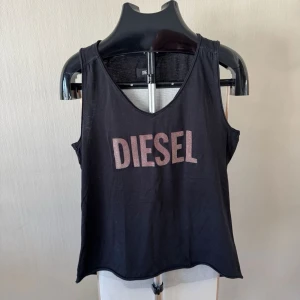 Svart linnetopp från Diesel - Snygg svart linnetopp från Diesel med stort logotryck framtill i rosa. 0420