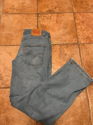 Levi's ljusblå raka jeans - Klassiska ljusblå jeans från Levi's med rak passform och femficksmodell. Jeansen har den ikoniska röda Levi's-lappen på bakfickan och läderpatch i midjan. Tillverkade i slitstark denim, perfekta för en avslappnad och tidlös stil.