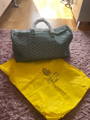 Grön G*Y weekendbag  - Snygg grön weekendbag med klassiskt mönster och detaljer i grönt läder. Väskan har dubbla handtag, avtagbar axelrem och medföljer en gul dustbag. Perfekt för resor och weekendäventyr.
