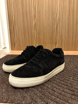 Svarta sneakers från Axel Arigato - Säljer ett par svarta sneakers från Axel Arigato med ovandel i mocka och klassisk snörning. De är unisex och nypris ligger runt 3 000kr.