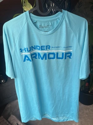 Träningströja Under Armour – Ljusblå (S / Loose fit) - Träningströja från Under Armour i ljusblå färg. Stor UA-logga och tryck på bröstet samt den klassiska loggan bak i nacken. Skön "Loose fit"-modell som ger god rörelsefrihet under träningen. ♡