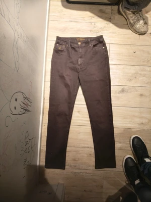 Bruna skinny jeans med hög midja - Snygga bruna skinny jeans med hög midja och klassisk femficksdesign. Jeansen har smal passform och raka ben, perfekta till en avslappnad eller trendig look. Materialet känns mjukt och stretchigt för extra komfort. 