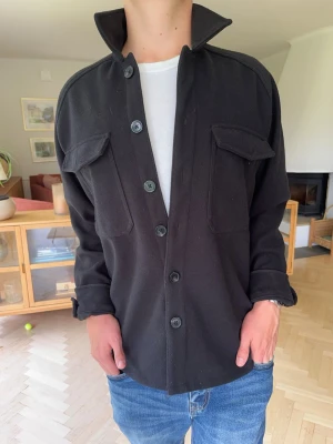 Smog overshirt svart herr - Stilren svart overshirt / shacket från Smog! 🕶️Klassisk svart skjortjacka med skön struktur. Modellen har rejäla bröstfickor och matchande svarta knappar. Perfekt som ett tunnare ytterplagg eller som ett stiligt lager-på-lager-plagg. I jättefint skick och redo för en ny ägare!#smog #overshirt #shacket #skjortjacka #herrjacka #svart #menswear #casualstyle #streetstyle #vintedse