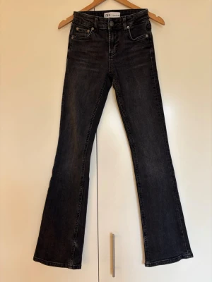 Svartgrå bootcut jeans från Zara storlek 32 - Snygga svartgrå bootcut jeans från Zara med klassisk femficksmodell. Jeansen har en lätt utsvängd passform nedtill och är tillverkade i ett mjukt denimtyg med stretch. Storlek 32. En pytteliten reva längst ned på höger byxben - se sista bilden, osynlig när de bärs