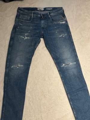 Blå slitna jeans från Replay - Säljer ett par skit feta replay jeans i helt nytt skick, storlek 34. Hör av dig vid frågor eller funderingar!