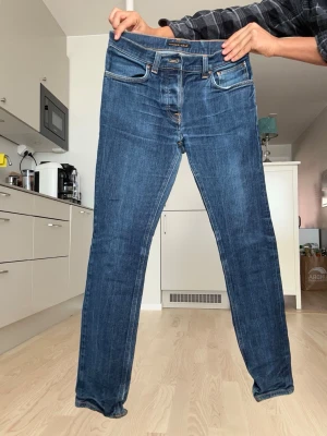 Nudie jeans - Säljer dessa raw denim jeans med sköna fades. Mått: midja 36 cm, längd 98 cm. Skick 7/10. Gammal slitning/skada vid inre lår. Går lätt o fixa själv eller hos skräddare. Hör av er vid frågor!