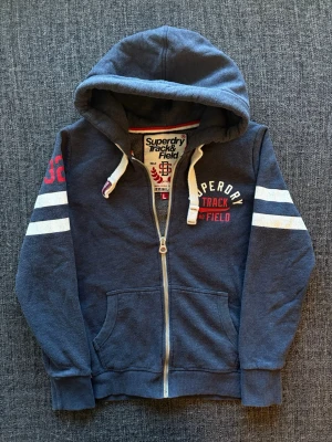 Superdry zip up ~ sällsynt  - Säljer nu denna sjukt snygga Superdry zip up hoodien | st L ~ sitter som XS/S, passar ca 166–178cm | marinblå färg som passar perfekt nu till kyligare dagar! Modellen produceras inte längre och är därav väldigt sällsynt. Kan även gå ner lite i pris vid snabb affär🍁🫶 