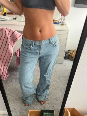 Ljusblåa raka jeans med låg midja - Säljer ett par ljusblå jeans med rak / baggy passform och låg midja. Jeansen har klassiska fem fickor och är tillverkade i denim. Slitna nere vid fötterna som visas på sista bilden, men de är långa så ofta så syns det inte så mycket!