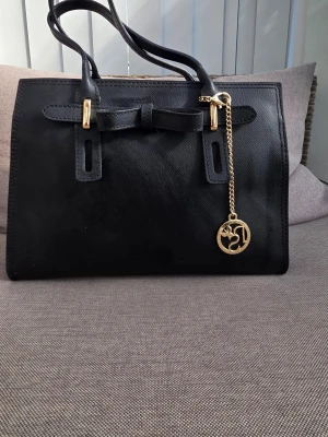 Svart tote - Stilren svart handväska i italienskt läder, med dubbla handtag och guldfärgade metalldetaljer. Mått 30x22x12