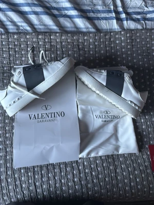 vita sneakers med mörkblå detaljer  - Säljer ett par vita sneakers med mörkblå detaljer med bred mörkblå rem över mitten och vita snören. Skorna har en chunky sula med nitar längs kanten och är tillverkade i slätt läder. Klassisk och stilren design med logga på tungan. Skorna är använd några gånger så lite smutsig och lite creasad.