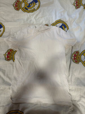 Vit basic t-shirt i bomull (6st) - En enkel vit t-shirt i mjuk bomull med rund hals och korta ärmar. Perfekt att matcha med jeans eller shorts för en clean och avslappnad stil. Passformen är normal och tyget är tunt och skönt.