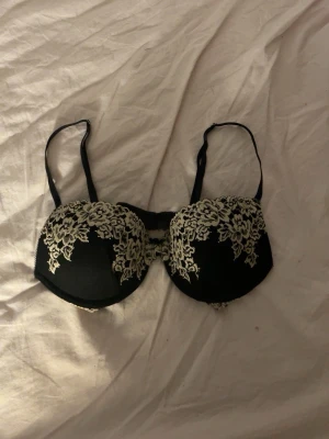 Svart spets-bh från H&M 75C - Snygg svart bh från H&M i storlek 75C med vadderade kupor och vacker beige spetsdetalj över kuporna. Justerbara axelband och hakknäppning bak. En dupe av en populär BH från intimissimi