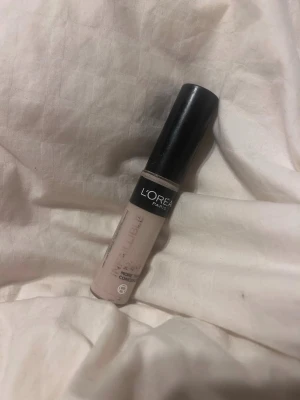 L'Oréal Infaillible Concealer 320 Cool Rose - Ljus concealer från L'Oréal Paris i nyansen 320 Cool Rose. Kommer i en smidig tub med svart lock och applikator. Perfekt för att täcka mörka ringar och ojämnheter. Ger ett naturligt resultat och är enkel att blenda in i huden. Har använt några gånger.