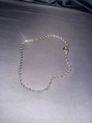 Cordel halsband  - Säljer ett stilrent halsband i silverfärg med tvinnad kedja. Halsbandet har en enkel och klassisk design som passar till många olika stilar. Materialet är stål och låset är av karbinmodell. 