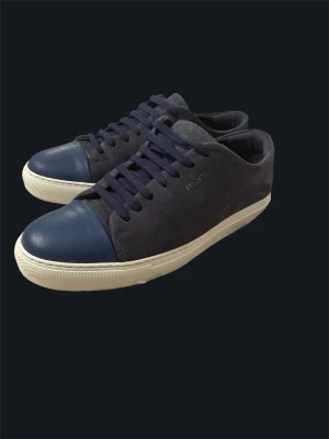 Axel Arigato Clean 90 Sneakers, Strl 42 - Säljer ett par stilrena Axel Arigato Clean 90 i mörkblå mocka med blå tådetalj i läder. En tidlös modell som passar lika bra till jeans som mer uppklädda outfits.  Skorna är i fint använt skick och har gott om liv kvar. Normalt slitage från användning, inga större skador. Storlek 42.  Nypris ligger runt 3 000 till 3 500 kr 