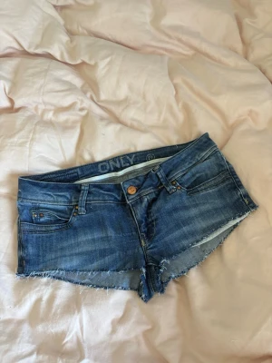 Blå jeansshorts från ONLY - Ett par Only jeansshorts. Low waist och väldigt snygga!! Storlek 27!