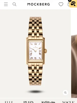 Mockberg klocka  - Stilren klocka från Mockberg med rektangulärt vitt ur och romerska siffror. Armbandet är i guldtonad metall med klassisk länkdesign. Perfekt accessoar för dig som gillar elegant och tidlös stil. Finns extra länkar att sätta dit så den passar dig. Använd ca 3 gånger. Finns låda till klocka med! 