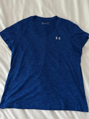 Under Armour t-shirt - Snygg blå t-shirt från Under Armour med v-ringning och korta ärmar. Tillverkad i ett lätt och funktionellt material som passar perfekt till träning🩵