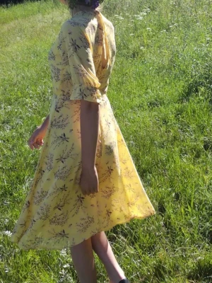 Gul blommig midiklänning med volang - Söt gul klänning med blommigt mönster, halvlånga ärmar med volangkant och knytning i nacken. Klänningen har ett medföljande bälte i midjan och är tillverkad i ett lätt, flowy material. Perfekt för soliga dagar och sommarens alla tillfällen.
