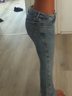 Lågmidjade jeans med broderad ficka - Säljer ett par ljusblå jeans med flare passform ned mot benen samt låg midja. Jeansen har en snygg broderad bakficka och klassiska bälteshällor. Perfekta till en avslappnad stil och passar till det mesta. Materialet är denim i bomull.
