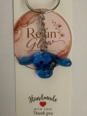 handgjord resin nyckelring - Unik handgjord nyckelring i blått resin med söt figurdesign. Nyckelringen har en metallkedja och ring, perfekt att hänga på väskan eller nycklarna. Figurerna är genomskinliga och har en lekfull, gullig stil som sticker. 