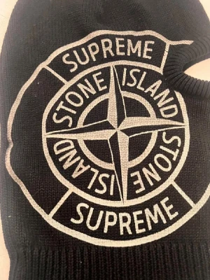 Svart balaclava Supreme x Stone Island - Säljer en svart balaclava från Supreme x Stone Island med stort broderat logomärke framtill. Mössan är ribbstickad och har ett hål för ögonen. Perfekt för dig som vill sticka ut med streetwear-vibe och exklusiv känsla.