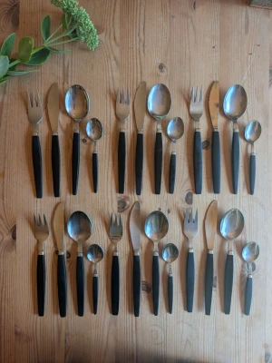 Bestickset med svarta handtag - Säljer ett bestickset med svarta handtag i bakelit och rostfritt stål. Setet innehåller gafflar, knivar, matskedar och teskedar. Handtagen är mattsvarta och har en avsmalnande form som ger ett modernt intryck. Perfekt till köket eller som extra bestick till festen.