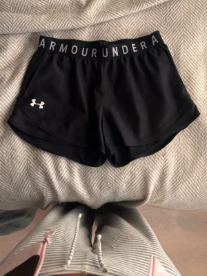 Svarta träningsshorts Under Armour - Säljer ett par svarta träningsshorts från Under Armour med bred resår i midjan där loggan står tryckt. De är jätte sköna me stora fickor❤️