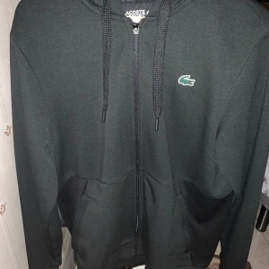 Lacoste Zip Hoodie  - En Lacoste zip Hoodie i väldigt fint skick. Tröjan är knappt använd och är därför i väldigt bra skick. Hoodien är i storlek M och är perfekt nu inför kallare dagar. Nypris 1699 Mitt pris 750 Hör av er vid eventuella frågor.