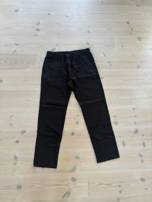 Svarta linnebyxor HM - Säljer ett par svarta linnebyxor med rak passform och resår i midjan samt dragsko. Byxorna har en enkel och clean look, perfekta för chill dagar eller när du vill vara bekväm. Materialet känns mjukt och stretchigt.