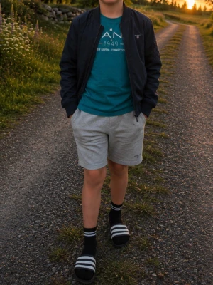 Mörkblå vårjacka från Gant st 34 - Stilren mörkblå vårjacka från Gant med klassisk passform, ribbade muddar och dragkedja framtill. Jackan har två fickor med tryckknapp och diskret logga på bröstet. Perfekt för en vårdag eller sommarkväll 