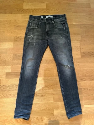Svarta slim fit jeans med slitningar 29/32 - Säljer ett par svarta slim fit jeans med snygga slitningar och tvättade detaljer. Jeansen har fem fickor, dragkedjegylf och smal passform. Perfekta för en avslappnad och trendig look. 29/32