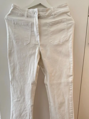 Vita raka jeans med hög midja - Snygga och stilrena vita jeans/byxor från Kappahl i storlek 38. Modellen har en smickrande passform med lätt raka och två utanpåfickor framtill som ger en fin detalj. Tillverkade i ett mjukt och skönt material med stretch. High waist.