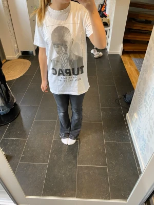Vit oversized Tupac t-shirt - Säljer en vit oversized t-shirt med stort Tupac-tryck på framsidan och texten 'Only God Can Judge Me'. T-shirten har korta ärmar och rak passform. Perfekt för dig som gillar streetwear och vill ha en statement piece i garderoben.