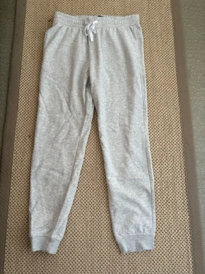 Ljusgrå mjukisbyxor  - Säljer ett par ljusgrå mjukisbyxor med resår i midjan och vit dragsko. Byxorna har muddar vid bensluten och är tillverkade i mjukt, stretchigt material. Perfekta för chill dagar eller när du vill vara extra bekväm. Väldigt bra skick