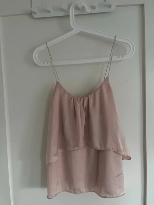 Ljusrosa volang topp från Gina Tricot  - Säljer en söt ljusrosa linnetopp med tunna axelband och dubbla lager tyg som ger en volangig look. Toppen har en lös passform och är från Gina tricot. Det är bara att skriva om de finns några frågor!💕